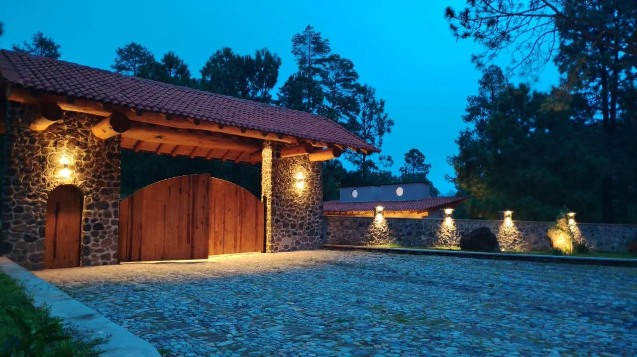 Ingreso controlado de Tlalli Residencial visto en ángulo, con caseta de piedra y camino empedrado