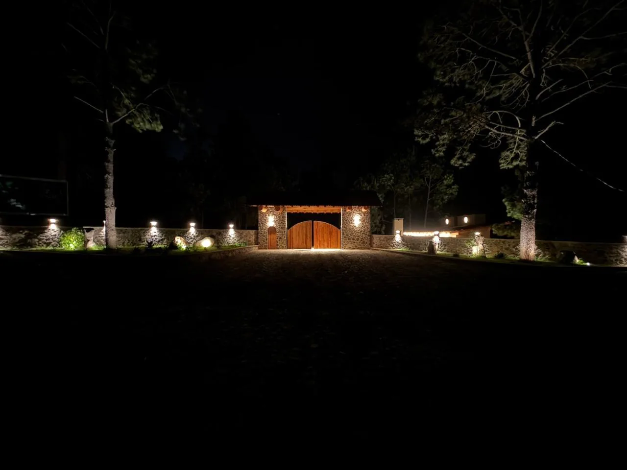Ingreso de Tlalli Residencial de noche, con el portón cerrado y toda la iluminación encendida