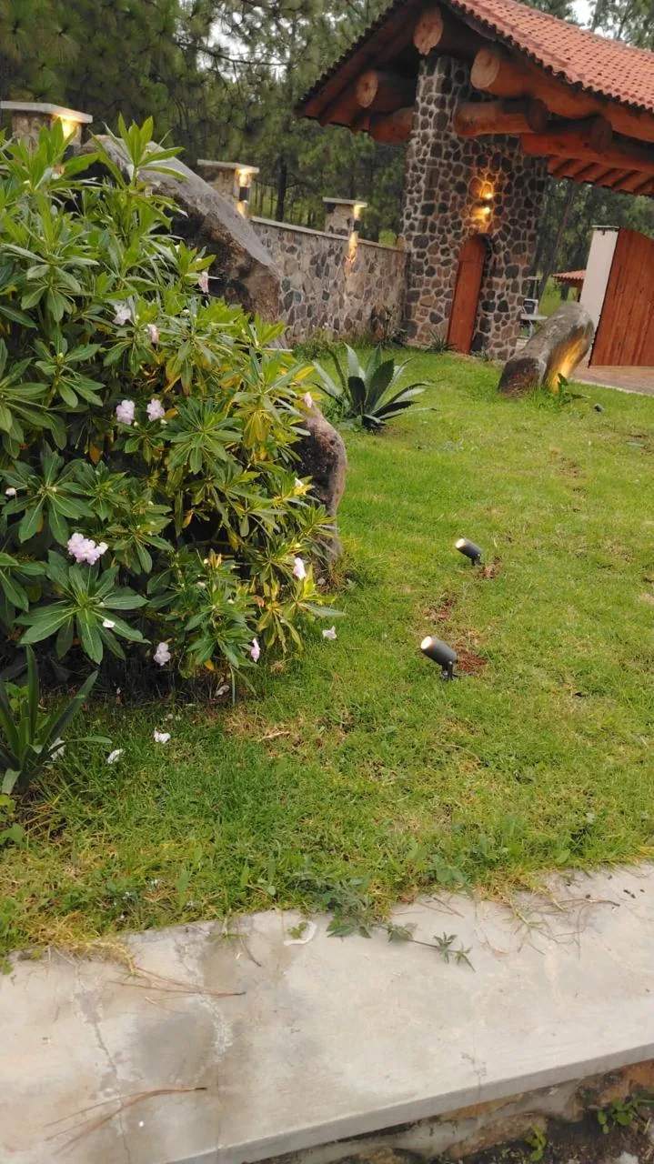 Jardín con flores y piedra volcánica frente a la caseta de acceso de Tlalli Residencial